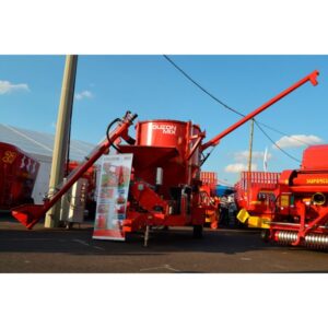 Broyeur à céréales rouge sur chassis routier avec vis de chargement et de déchargement. Présent au Sommet de l'élevage.